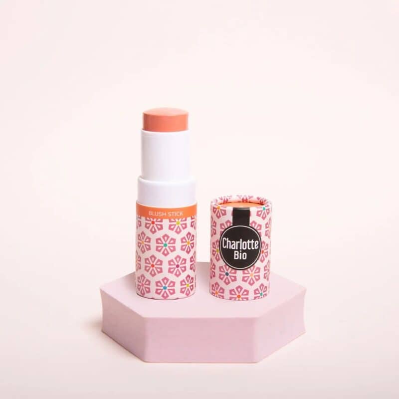 Charlotte Bio Blush Stick met decoratieve verpakking met roze bloemenpatroon, getoond op roze hexagon display